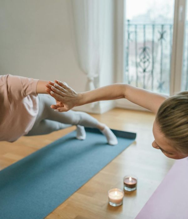 Жінка виконує м'яку розтяжку у світлому, спокійному просторі.