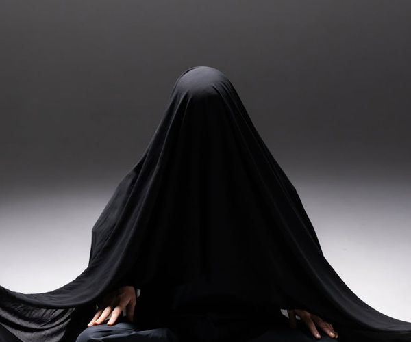 Жінка в спокійній медитаційній позі у м'яко освітленій студії.